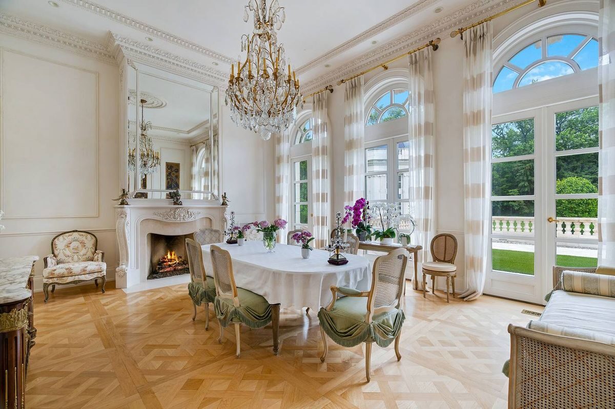 Bright classical salon with chandelier, fireplace, and arched doors